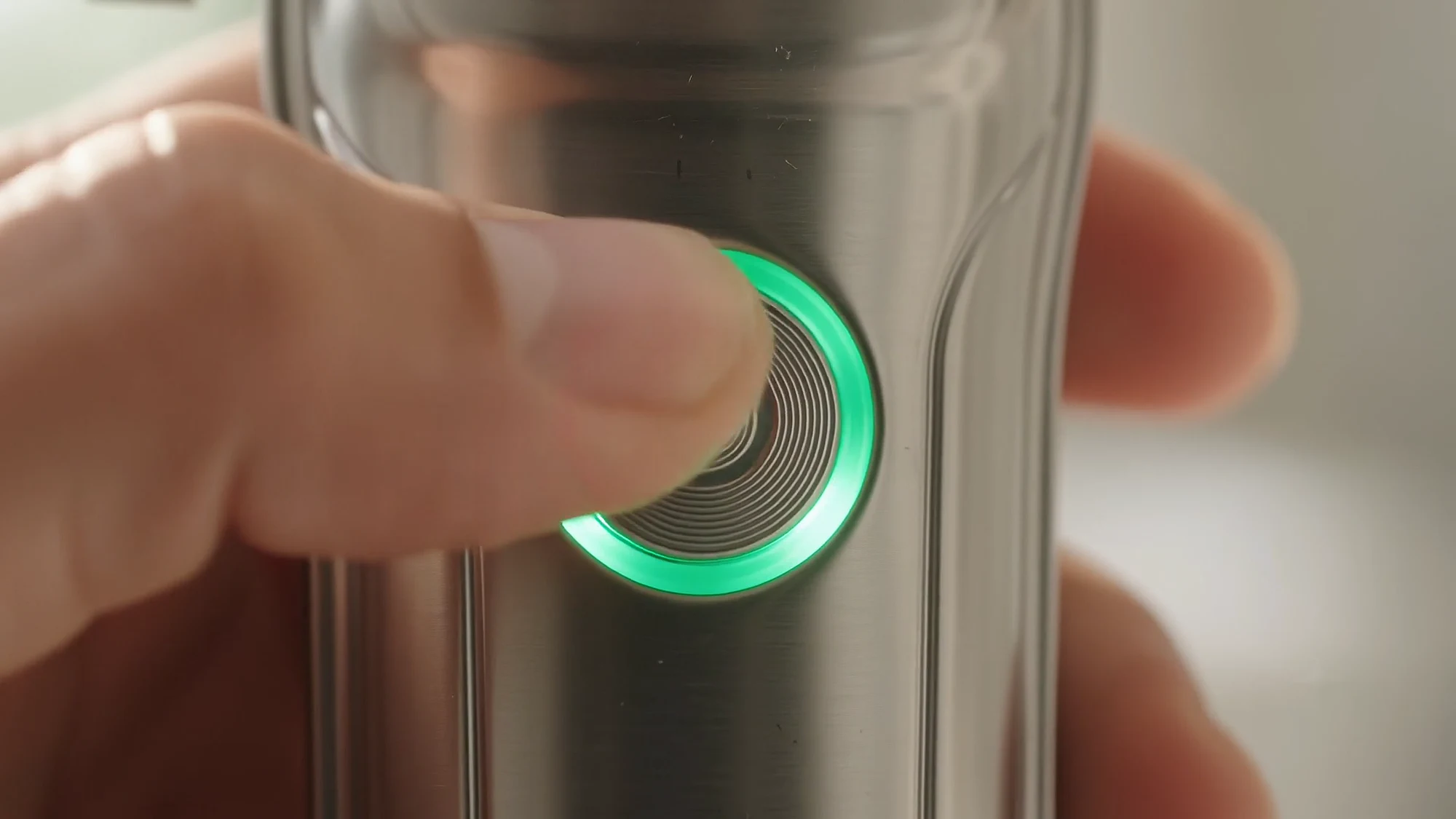 A thumb presses the power button and a green ring lights up