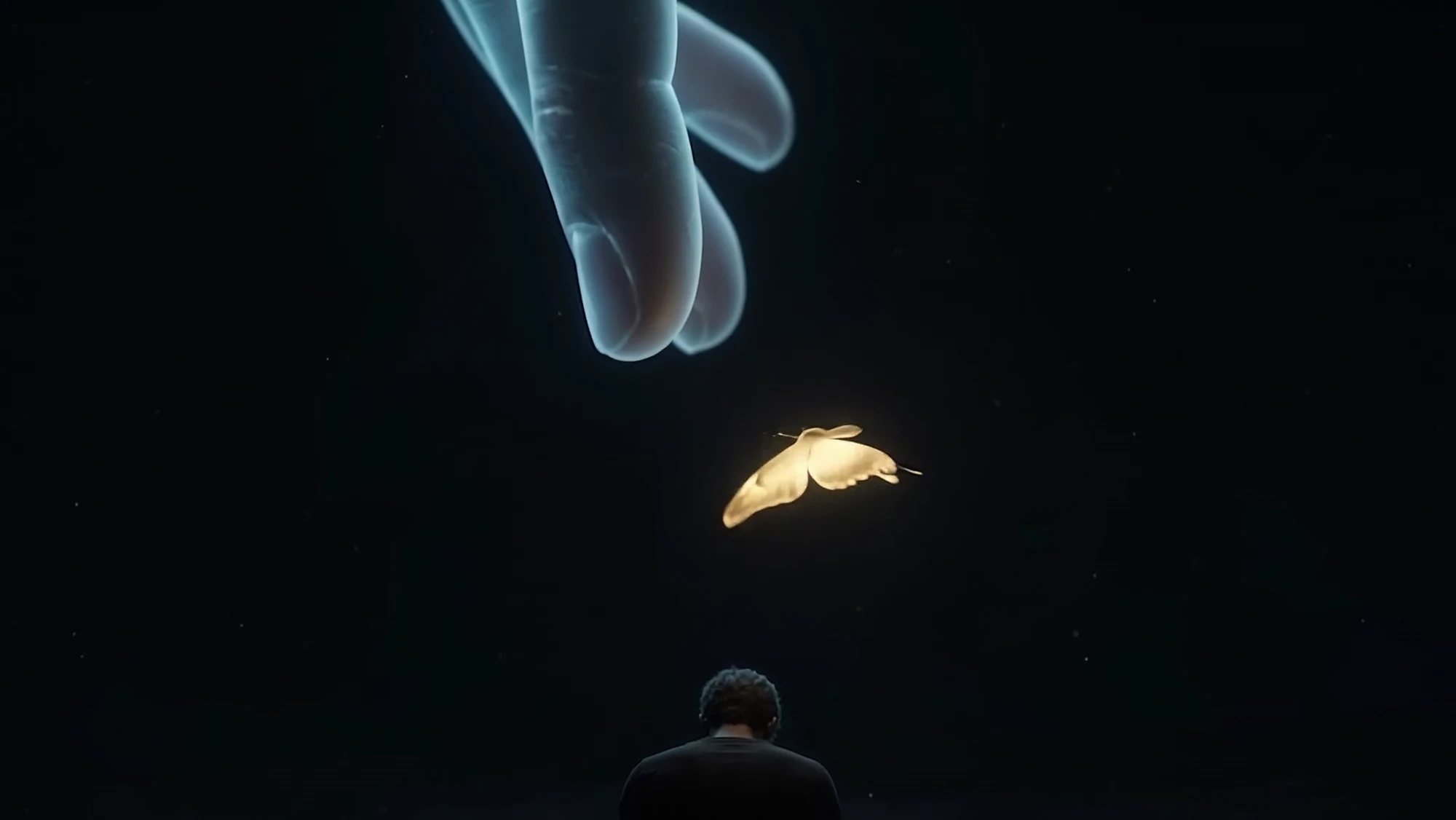 The golden butterfly leaving the hand and drifting down toward a person sitting in the dark