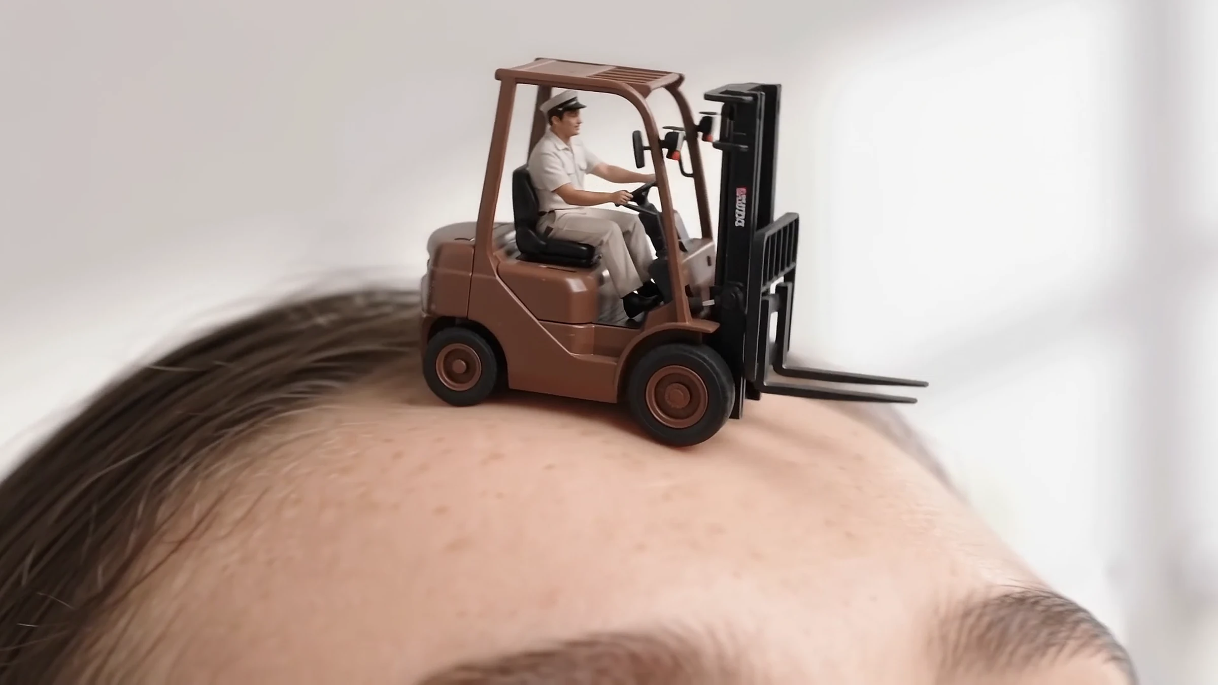 A toy forklift with a driver parked on a model's forehead