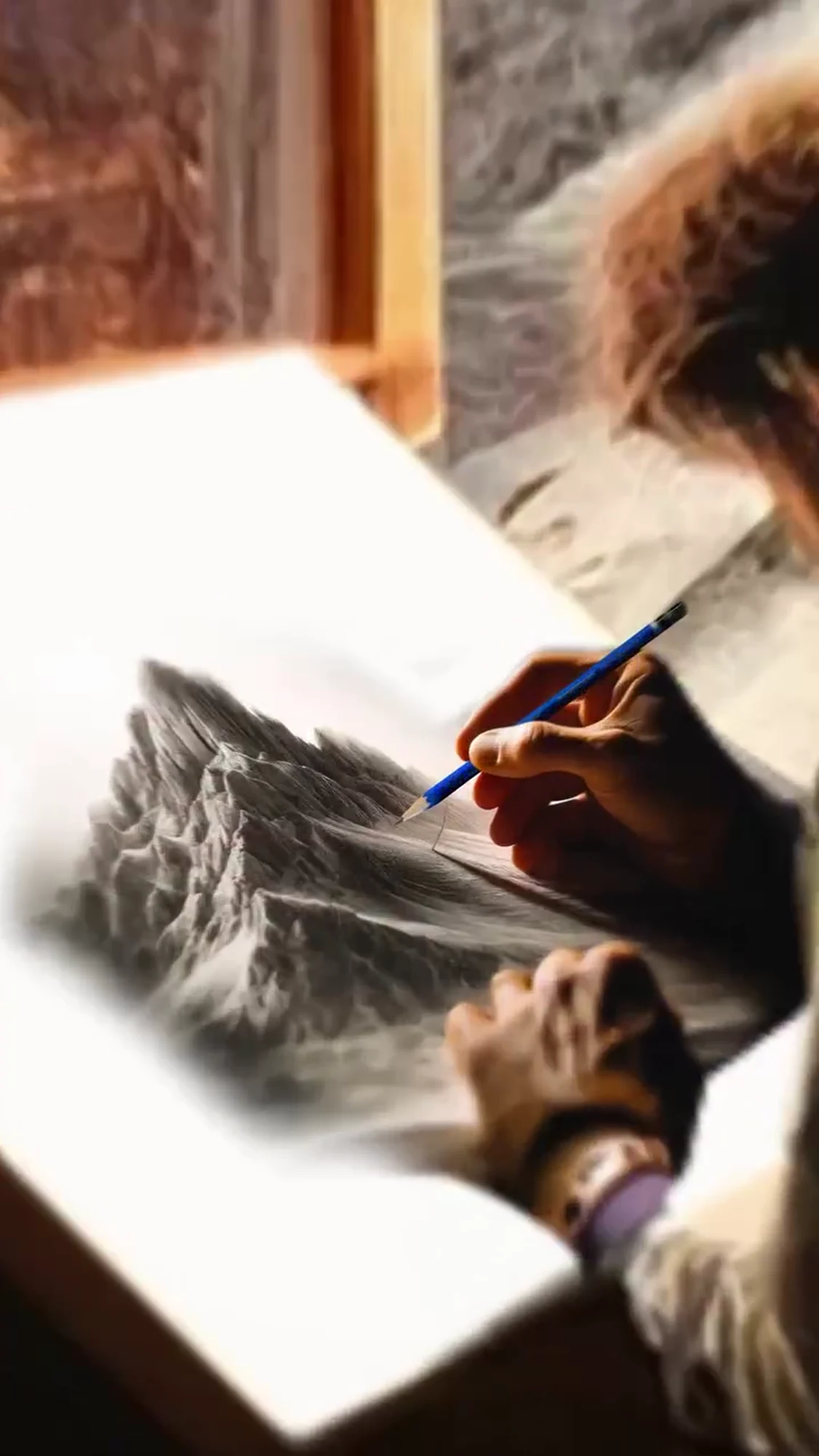 A hand drawing a mountain landscape with a blue pencil