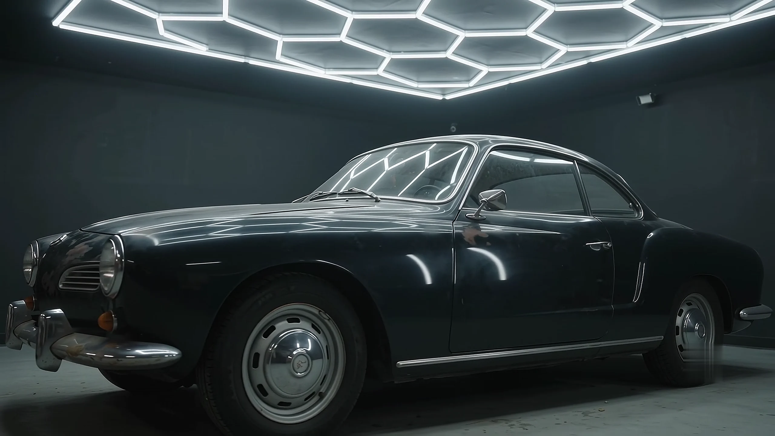 Restored dark coupe reflecting the studio's hexagonal lights