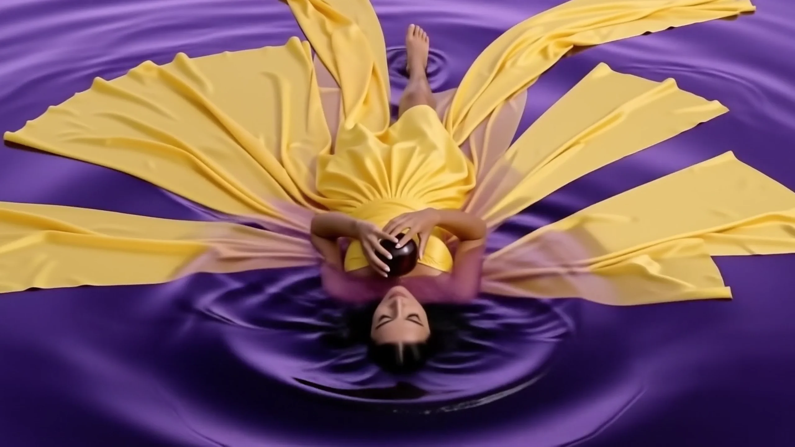 Golden dress floating as an abstract flower on violet water
